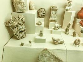 Museumsstück. Gipsmasken werden hinter dem Glas auf dem Ständer eingesetzt. Bilder von Gesichtern von Menschen, Skulpturen in Form von Tieren. uralte Kreativität foto