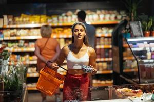 junge Frau kauft im Supermarkt ein. Blaubeere im Laden auswählen foto