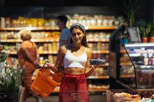 junge Frau kauft im Supermarkt ein. Blaubeere im Laden auswählen foto