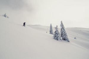 Skifahrer, der das Landschaftsfoto des Skihügels hinuntergeht foto