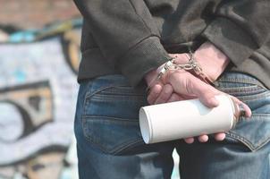 eine Rückansicht eines verhafteten Straßenkünstlers in Handschellen mit Eros foto