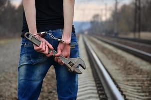 das Mädchen in Handschellen mit dem verstellbaren Schraubenschlüssel auf der Eisenbahn foto