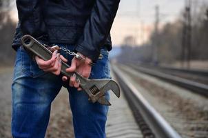 das Mädchen in Handschellen mit dem verstellbaren Schraubenschlüssel auf der Eisenbahn foto