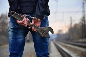 das Mädchen in Handschellen mit dem verstellbaren Schraubenschlüssel auf der Eisenbahn foto