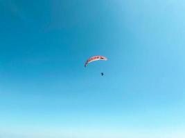 Fallschirmjäger fliegen durch die Luft. auf einen Gleitschirm springen. Blick auf die Stadt aus Flughöhe. roter Fallschirm. extreme Unterhaltung foto