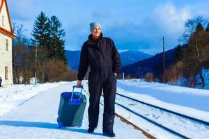 Mann in Winterkleidung steht auf dem Bahnsteig eines Bahnhofs foto
