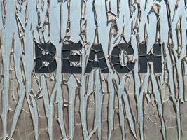 alte rissige Inschrift Strand in großen Buchstaben auf dem Teller. ein brutales Strandurlaubskonzept foto