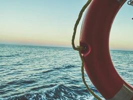 orange Rettungsring auf dem Schiff. Kreuzfahrt. Halbkreis. Rettungsausrüstung unter einer Markise vor dem Hintergrund des Meeres foto