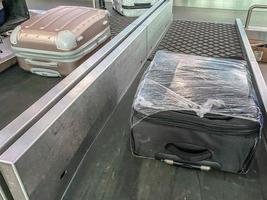 Gepäck auf dem Band am Flughafen. der koffer reist entlang der linie. Dinge sind gestapelt. der koffer ist in einer transparenten folie verpackt. Schutz und Sicherheit von persönlichen Gegenständen foto