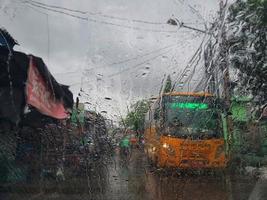 jakarta, indonesien im juli 2022. der zustand aus dem inneren eines autos, wo die windschutzscheibe des autos regnete und vor dem auto ein gelber schulbus vorbeifuhr foto