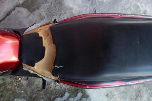 Zerrissener Motorradsitz, alter schwarzer Ledersitz ist beschädigt, gebrochenes Leder. foto