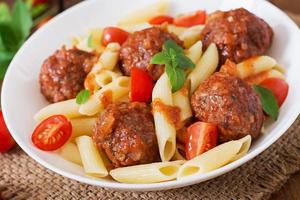 Penne-Nudeln mit Fleischbällchen in Tomatensauce in einer weißen Schüssel foto