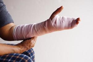 Nahaufnahme Hand mit Bandage am verstauchten Handgelenk gewickelt, Behandlung von Verletzungen am Arm. konzept, gesundheitsproblem, unfall, erste hilfe. Versicherung. foto
