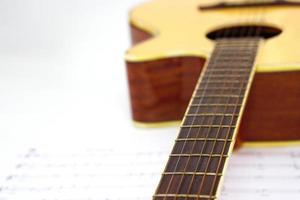 Akustikgitarre mit Musiknoten vor weißem Hintergrund und selektivem Fokus. Liebes- und Musikkonzept. Liebes- und Musikkonzept. foto