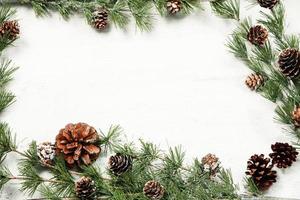 weihnachts- und neujahrshintergrund mit grünen fichtenzweigen und tannenzapfen, weiße fahne, draufsicht, kopierraum foto