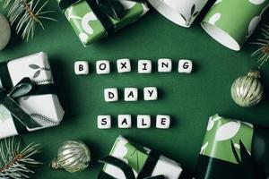 Boxing Day Sale Text auf grünem Hintergrund. verpackte Geschenkboxen und Tannenzweige. Ansicht von oben, flach liegend. Weihnachtsverkaufskonzept foto