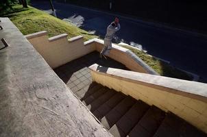 ein junger mann macht einen sprung durch den raum zwischen den betonbrüstungen. Der Athlet übt Parkour und trainiert unter Straßenbedingungen. das Konzept der sportlichen Subkulturen unter Jugendlichen foto