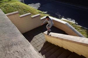 ein junger mann macht einen sprung durch den raum zwischen den betonbrüstungen. Der Athlet übt Parkour und trainiert unter Straßenbedingungen. das Konzept der sportlichen Subkulturen unter Jugendlichen foto