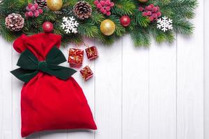 weihnachtshintergrund mit geschmücktem tannenbaum und roter geschenktüte. draufsicht, flach liegend mit kopierraum foto