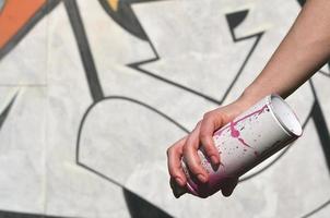 Foto der Hand eines Mädchens mit Aerosol-Farbdosen in den Händen auf einem Graffiti-Wandhintergrund. das Konzept der Straßenkunst und die Verwendung von Aerosolfarben. Graffiti-Kunstladen-Hintergrundbild