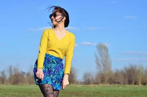 Attraktives und süßes brünettes Mädchen in einem gelben Pullover geht durch foto