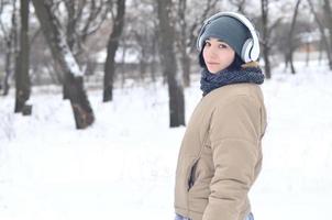 Winterportrait des jungen Mädchens mit Kopfhörern foto