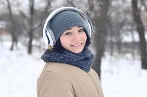 Winterportrait des jungen Mädchens mit Kopfhörern foto