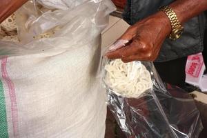 Der traditionelle Kerupuk-Verkäufer verpackt die verkauften Cracker foto