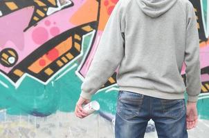 Ein junger Graffiti-Künstler in einem grauen Hoodie blickt mit auf die Wand foto