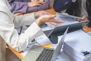 team business drei lächelnde und glückliche asiatische männer und frauen team mit tabletten und laptops brainstorming und plotten sie statistiken auf einer unternehmensdiagrammtafel innerhalb des unternehmens. Kollegen-Konzept. foto