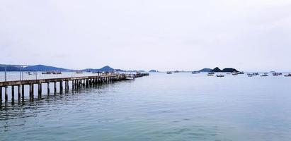 lange brücke zwischen meer oder ozean mit vielen booten und weißem himmelshintergrund in port phuket, thailand. Meerblick mit Berg und Natur mit foto