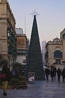 weihnachtsbaum auf der hauptstraße von valletta zur weihnachtszeit gegenüber dem parlamentsgebäude während der weihnachtsferien foto