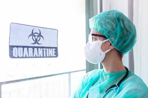 besorgte ärztin, die durch das krankenhausfenster schaut, quarantänewarnschild im krankenhaus mit arzt, krankenschwester mit maske und schutzanzug. Coronavirus-Ausbruch foto