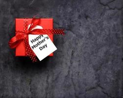 Draufsicht auf rote Geschenkbox und glückliche Muttertagskarte auf Schwarz foto