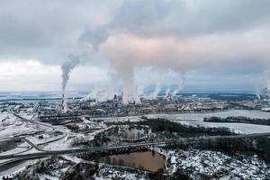 winterlicher Panoramablick auf den Rauch von Rohren eines Chemiewerks oder Holzverarbeitungsunternehmens. Konzept der Luft- und Wasserverschmutzung. foto