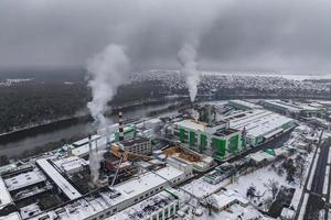 winterlicher Panoramablick auf den Rauch von Rohren eines Chemiewerks oder Holzverarbeitungsunternehmens. Konzept der Luft- und Wasserverschmutzung. foto