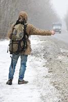 ein mann mit einem großen rucksack zeigt daumen hoch zum trampen du foto