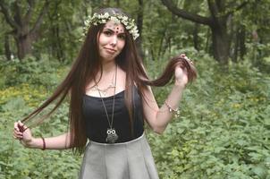 ein waldbild einer schönen jungen brünetten europäischer ausstrahlung mit dunkelbraunen augen und großen lippen. auf dem Kopf des Mädchens trägt sie einen Blumenkranz, auf der Stirn glänzende Verzierungen foto