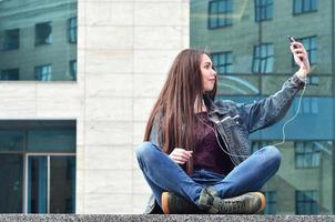 junges mädchen, das selfie auf dem hintergrund eines bürogebäudes macht foto