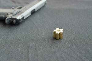 9-mm-Kugeln und Pistole liegen auf einem schwarzen Stoff. ein Satz Schießstandartikel oder eine Selbstverteidigungsausrüstung foto