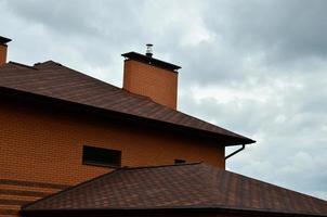Das Haus ist mit einer hochwertigen Dacheindeckung aus Schindeln aus Bitumenziegeln ausgestattet. ein gutes Beispiel für eine perfekte Überdachung. Das Dach ist zuverlässig vor Witterungseinflüssen geschützt foto
