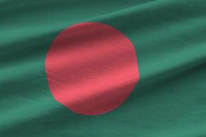 Bangladesch-Flagge mit großen Falten, die im Innenbereich unter dem Studiolicht wehen. die offiziellen symbole und farben im banner foto