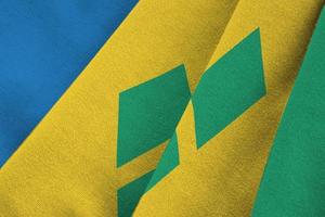St. Vincent und die Flagge der Grenadinen mit großen Falten, die in der Nähe unter dem Studiolicht im Innenbereich wehen. die offiziellen symbole und farben im banner foto