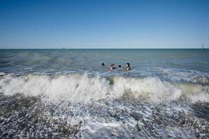 familie mit kindern schwimmen in der adria am strand von porto sant elpidio, italien. foto