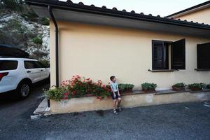 Junge sitzt in der Nähe von Haus in Nocera Umbra, Stadt und Gemeinde in der Provinz Perugia, Italien. foto