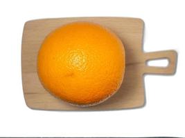 eine ganze Orange auf einem Schneidebrett. Fruchtisolat. saftige Orange auf dem Tisch. foto