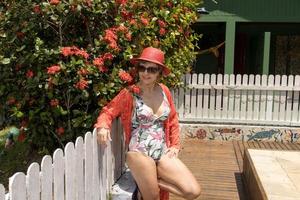 Frau, die einen einteiligen Badeanzug und eine farbenfrohe Vertuschung trägt, die an einem sonnigen Tag in der Nähe eines Pools hängt foto
