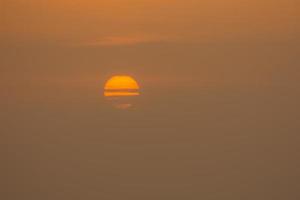 Halbbedeckte Sonne bei Sonnenaufgang am Meer im Detail Ägypten foto
