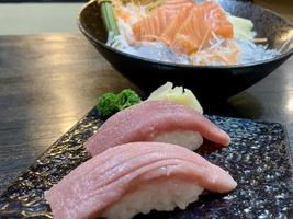 verschiedene Menüs, Sushi, Sashimi, Nigiri, gebratenes Schweinefleisch und Miso-Suppe. sashimi, chutoro sashimi, japanische essensstäbchen und wasabi auf dem schwarzen tisch, japanischer essensstil. verwischt den Fokus. foto