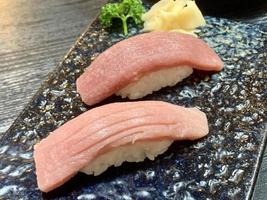 verschiedene Menüs, Sushi, Sashimi, Nigiri, gebratenes Schweinefleisch und Miso-Suppe. sashimi, chutoro sashimi, japanische essensstäbchen und wasabi auf dem schwarzen tisch, japanischer essensstil. verwischt den Fokus. foto
